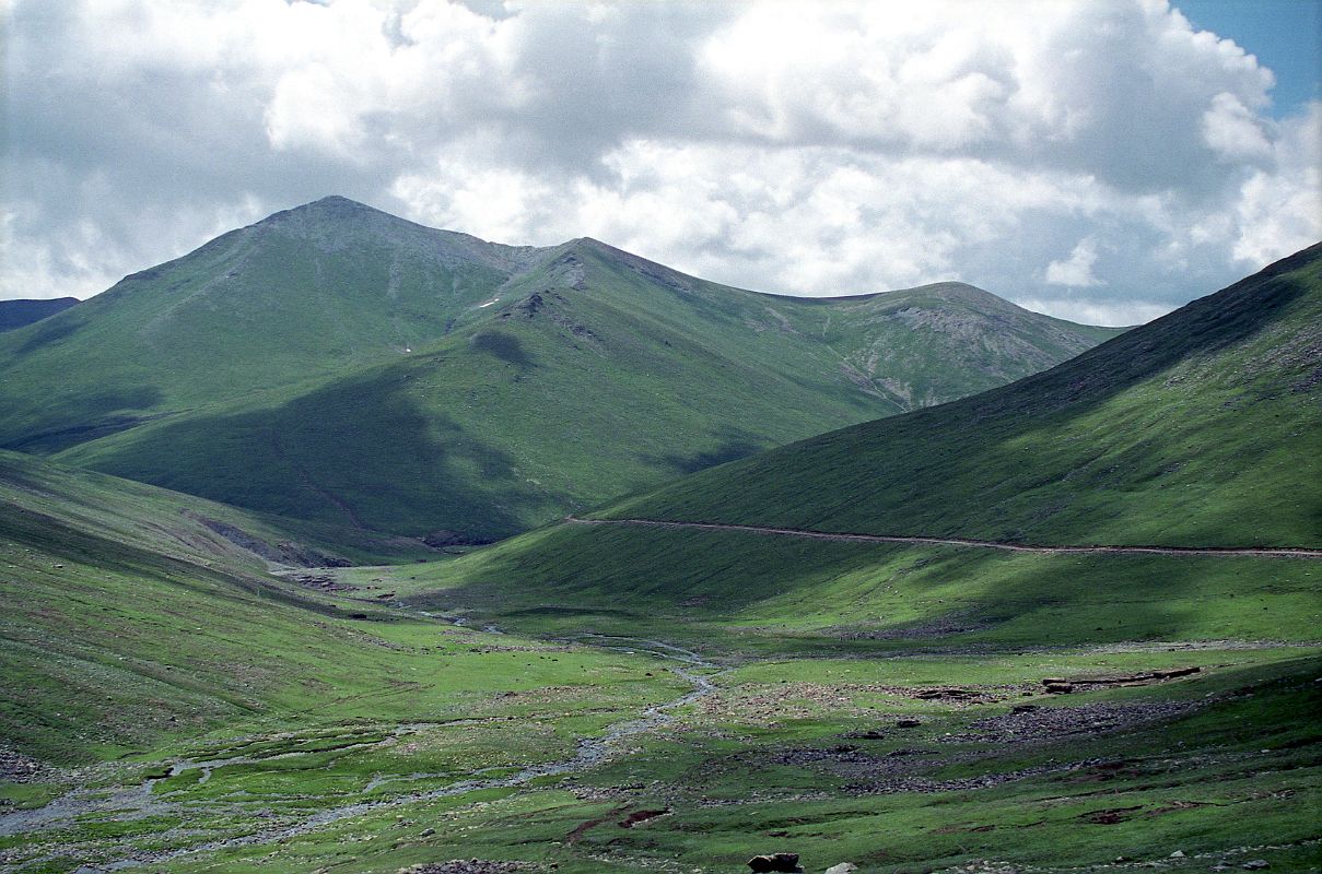 07 Road Between Babusar Pass And Lake Lulusar In Kaghan Vallery Over the Babusar Pass there is a barren green valley with patches of snow still clinging to the black mountain tops.